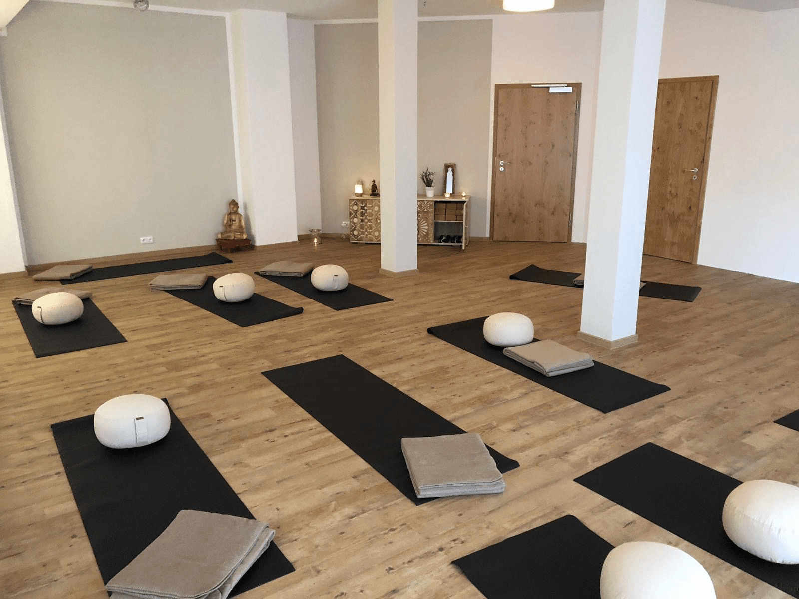 Yoga-Raum mit Holzboden, Matten und Buddha-Altar